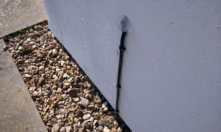 external cat5e ethernet cable going through hole in housewall on side of house and sealed with silicon sealant