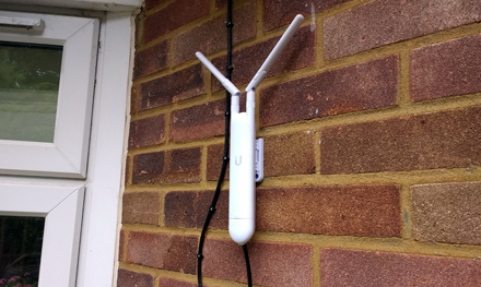 image of outdoor wireless access point installed outdoors on side of house to give wifi network coverage in garden by flying moth limited stevenage hertfordshire